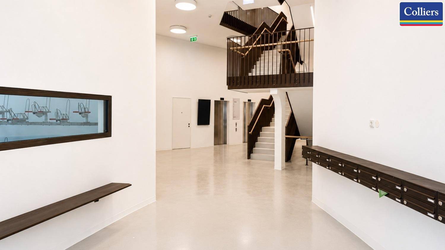 Heller Eingangsbereich mit Treppe, Aufzügen und Briefkästen in modernem Design, einladend und funktional.