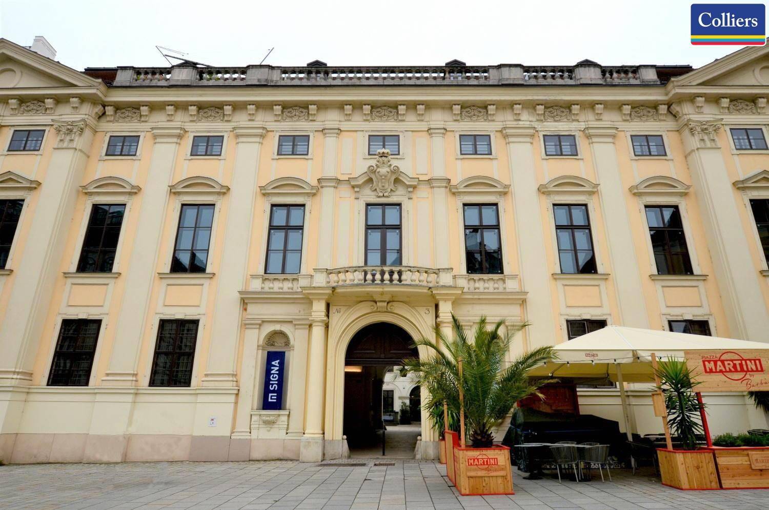Historische Fassade eines eleganten Gebäudes mit großen Fenstern und einem Balkon im klassischen Stil.