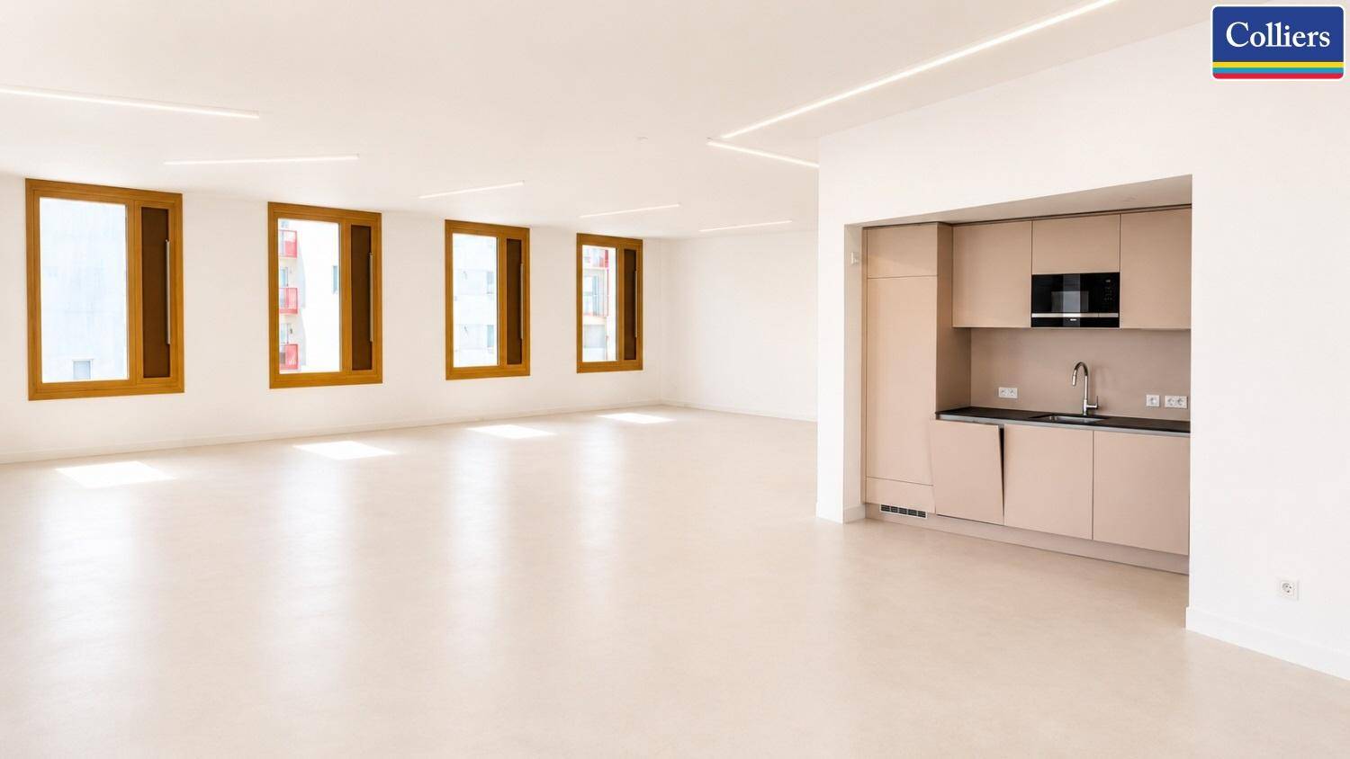 Moderne Küchenzeile in einem offenen Bürobereich mit integrierten Geräten und viel Licht.