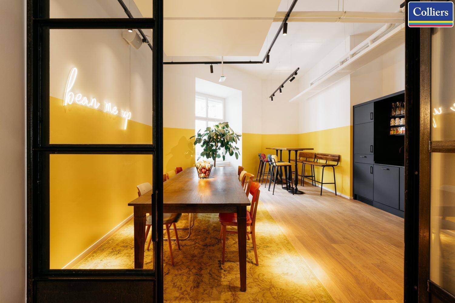 Heller Essbereich mit Holztisch, farbigen Stühlen und einer modernen Neon-Wanddekoration.