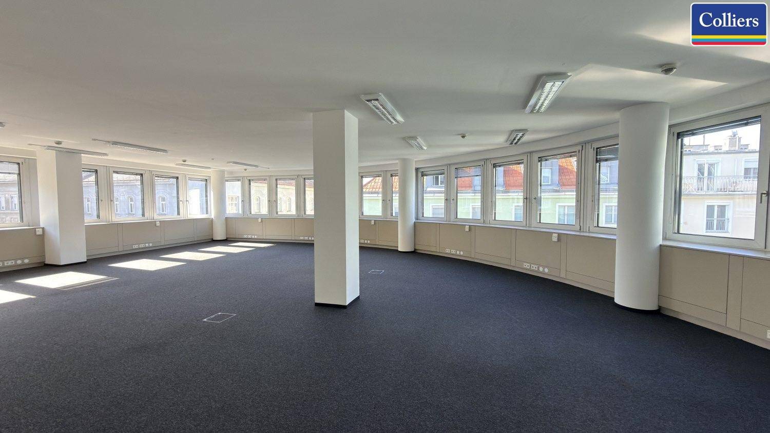 Großes, offenes Büro mit Teppichboden, runder Fensterfront und Säulen, bietet flexible Gestaltungsmöglichkeiten.