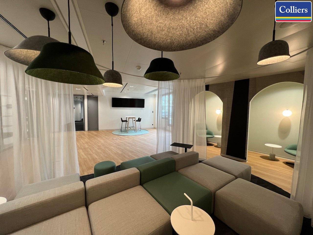 Kreativer Loungebereich mit modularen Sitzmöbeln, auffälligen Pendelleuchten und Vorhängen für eine gemütliche Atmosphäre.