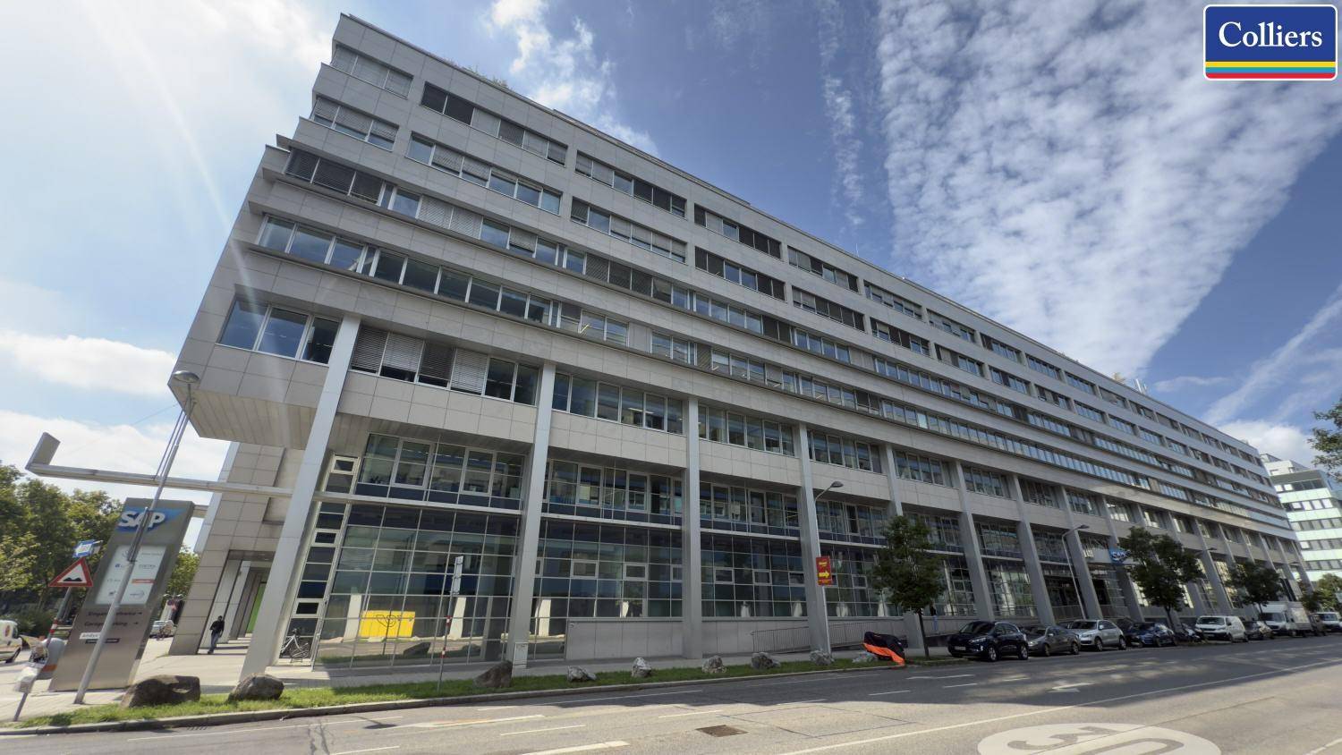 Großes Bürogebäude mit moderner Architektur, vielen Fenstern und einer belebten Straße davor.