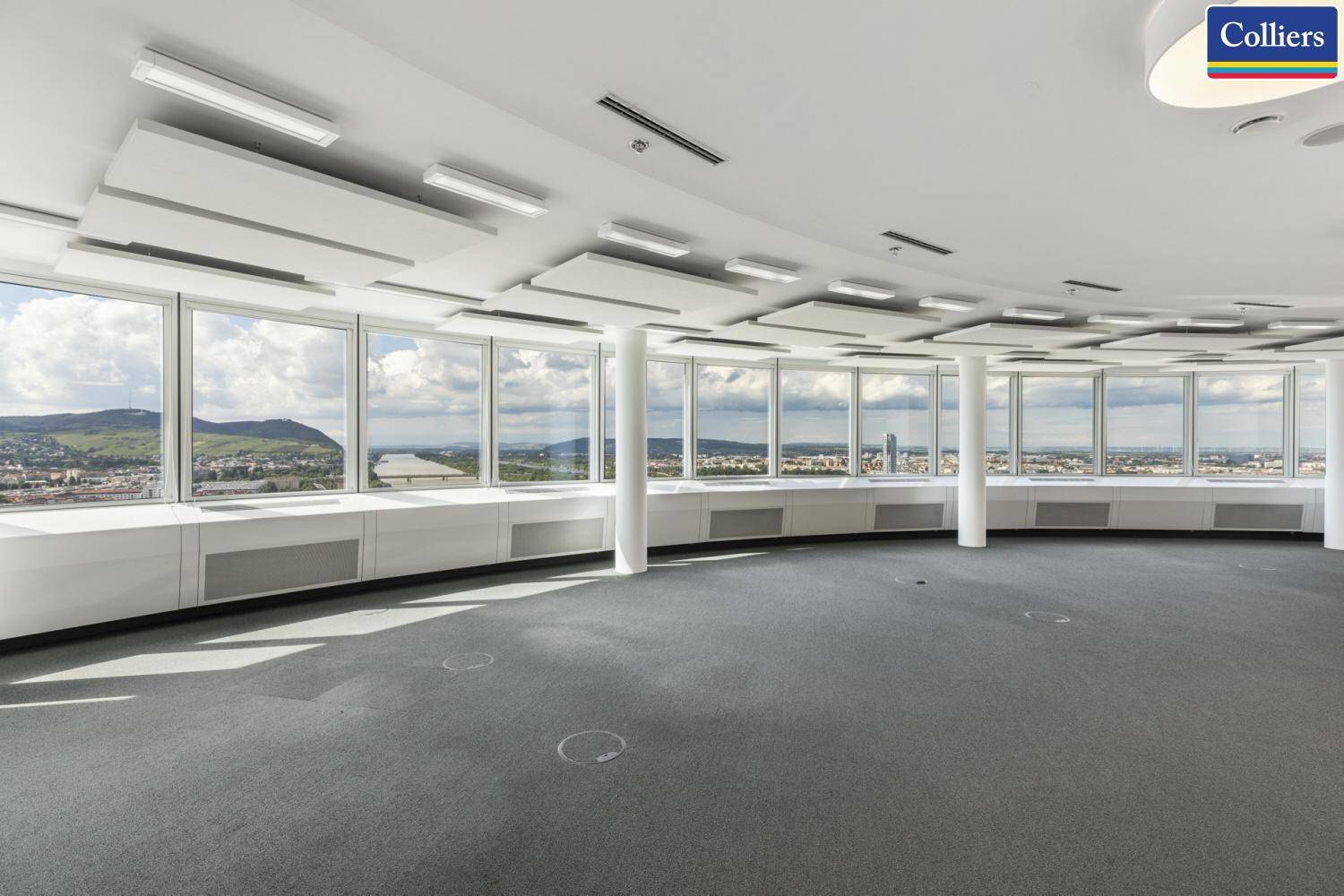 Weitläufiges, leeres Büro mit geschwungenen Wänden und Panoramafenstern mit Stadt- und Landschaftsblick.