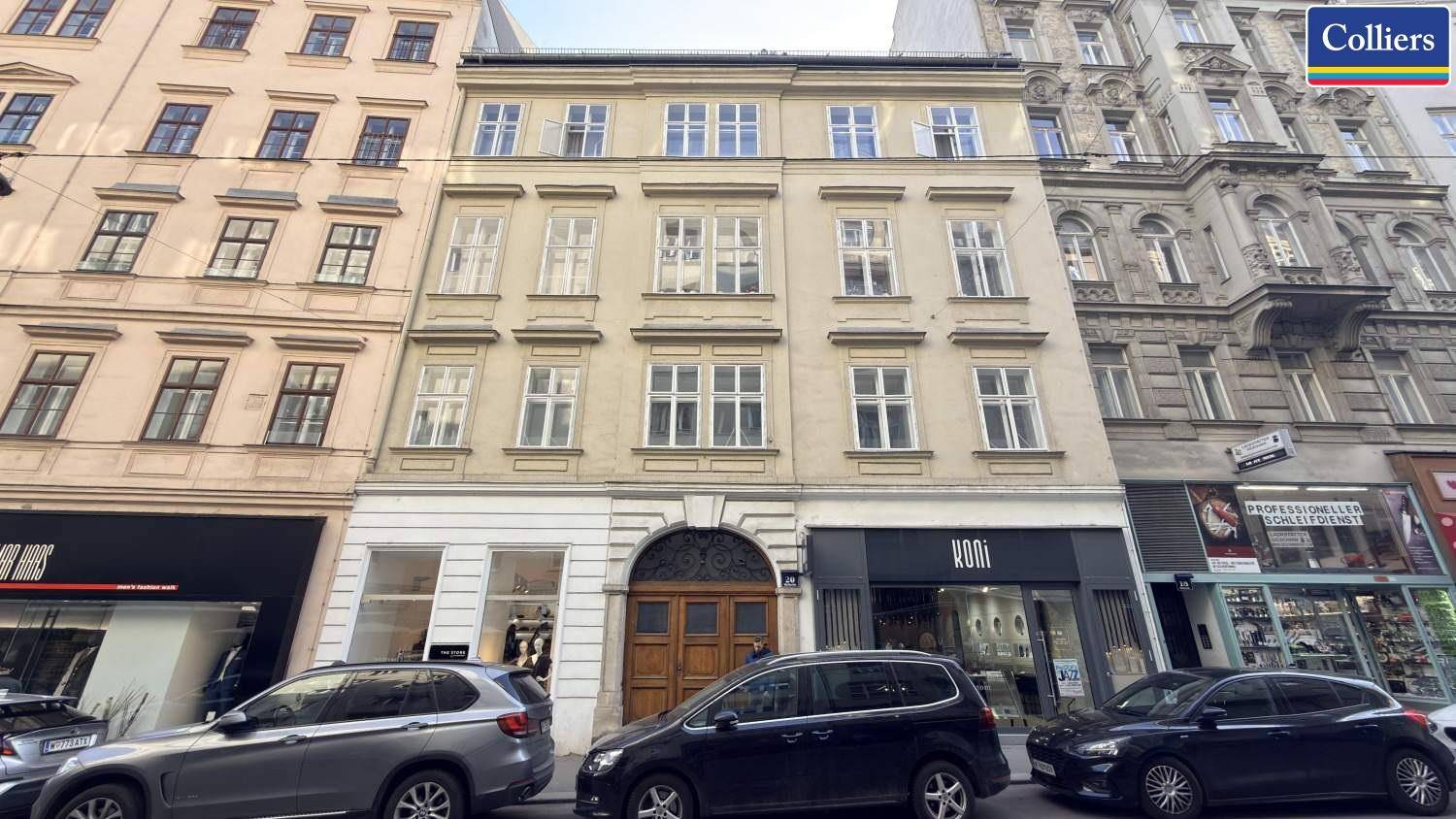 Historisches Gebäude mit Geschäften im Erdgeschoss und Wohnungen darüber, an einer belebten Straße.