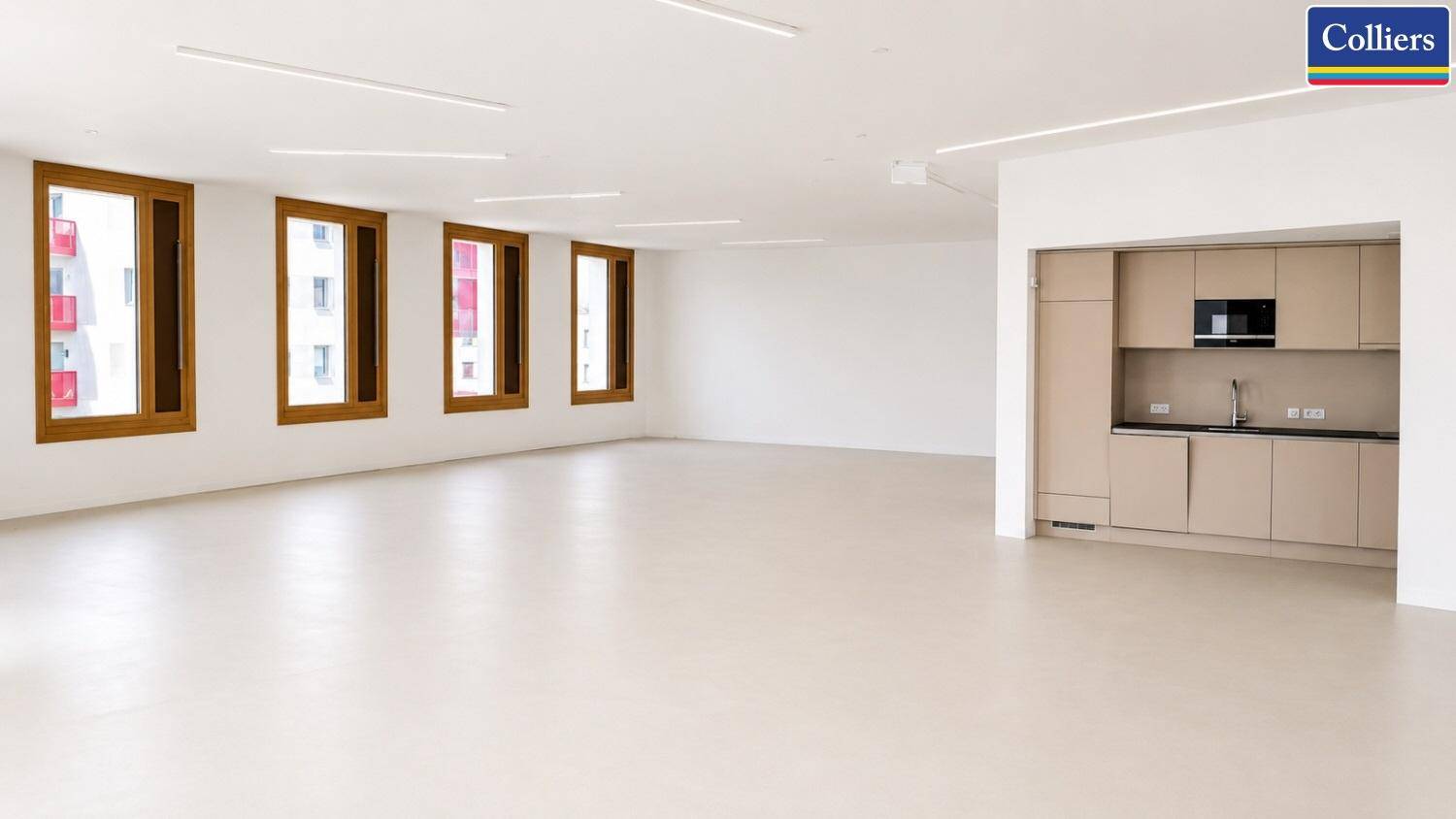 Offener Bürobereich mit integrierter Küchenzeile, großen Fenstern und viel Tageslicht für eine angenehme Atmosphäre.