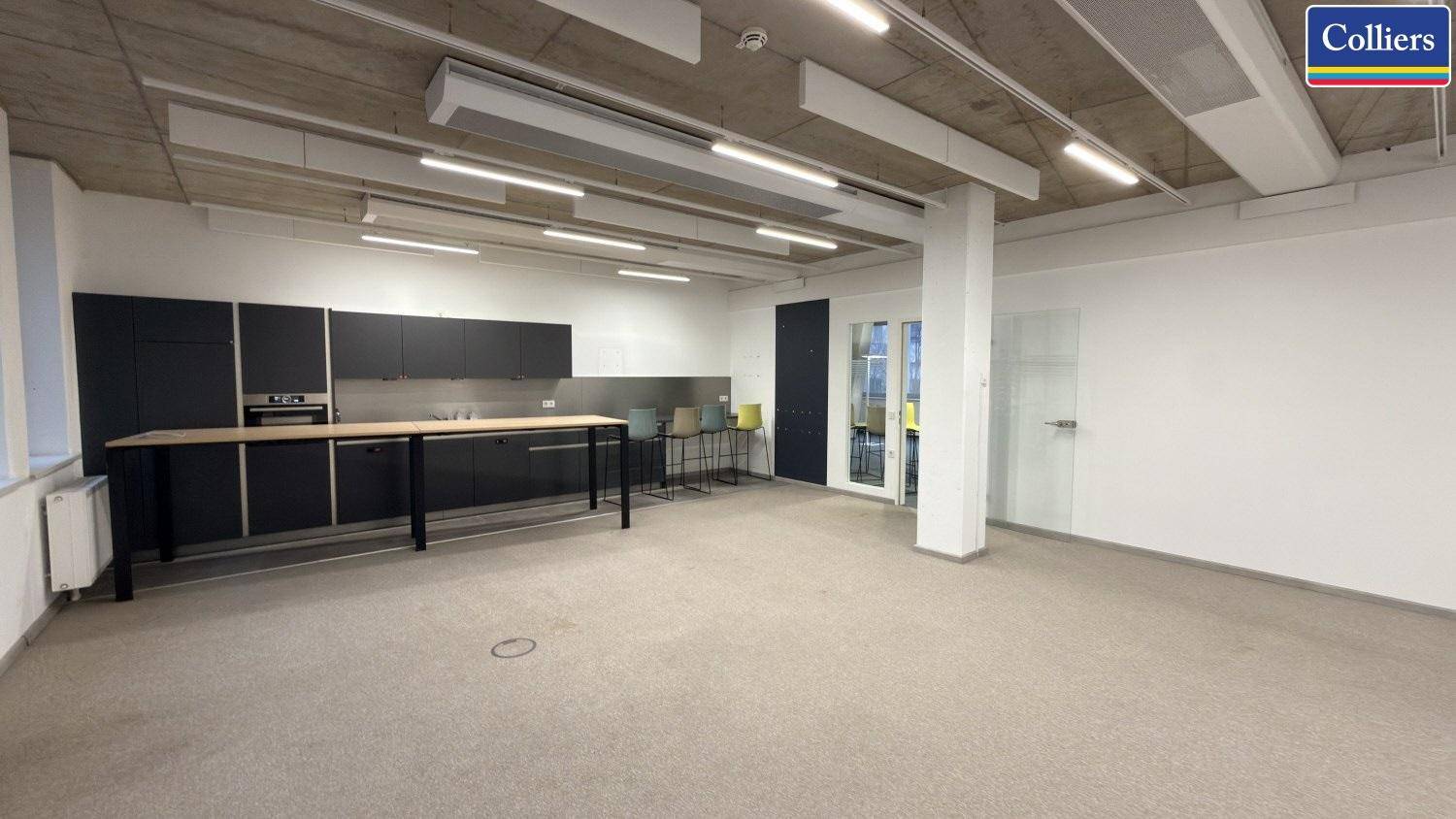 Moderne Gemeinschaftsküche mit schwarzen Schränken, Holztisch und hellem Teppichboden.