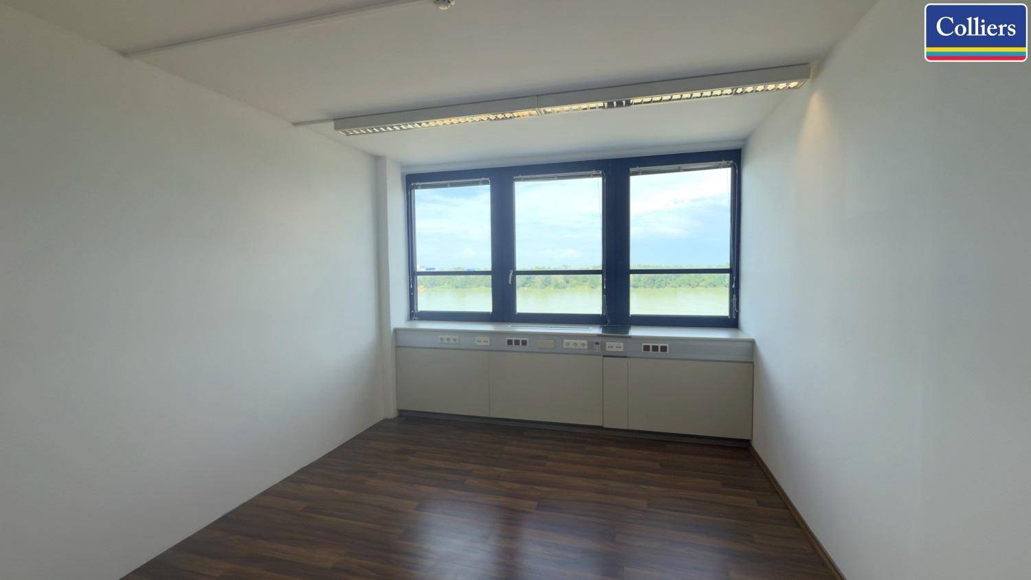 Büro mit Holzboden und einer breiten Fensterfront, die einen weiten Blick auf die Umgebung bietet.