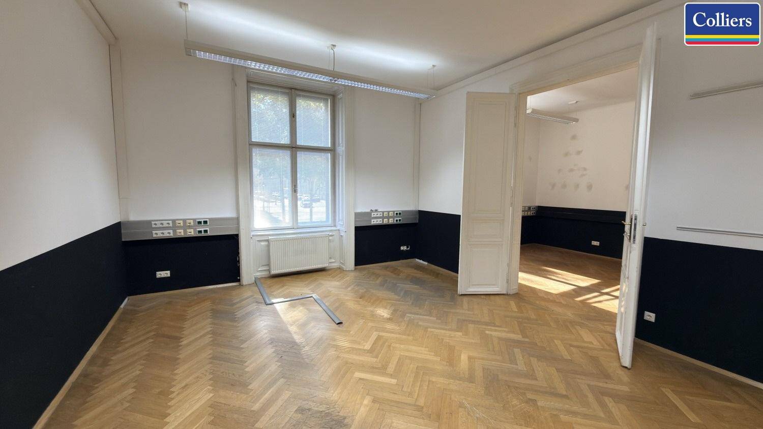 Helles Büro mit klassischem Fischgrätparkett und großen Fenstern, ideal für eine moderne Arbeitsumgebung.