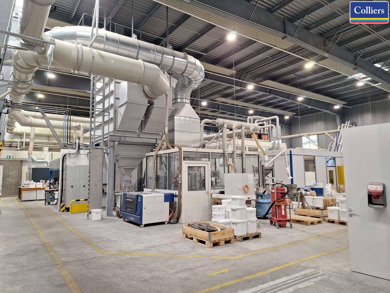 Produktionsbereich mit komplexen Maschinen, großen Lüftungssystemen und industrieller Ausstattung.