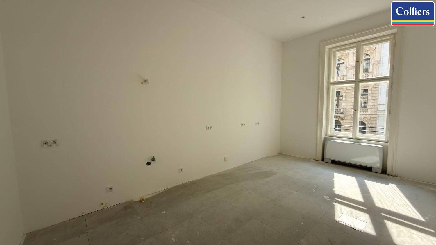 Leerer Büroraum mit weißen Wänden und einem großen Fenster, das den Blick nach draußen freigibt.