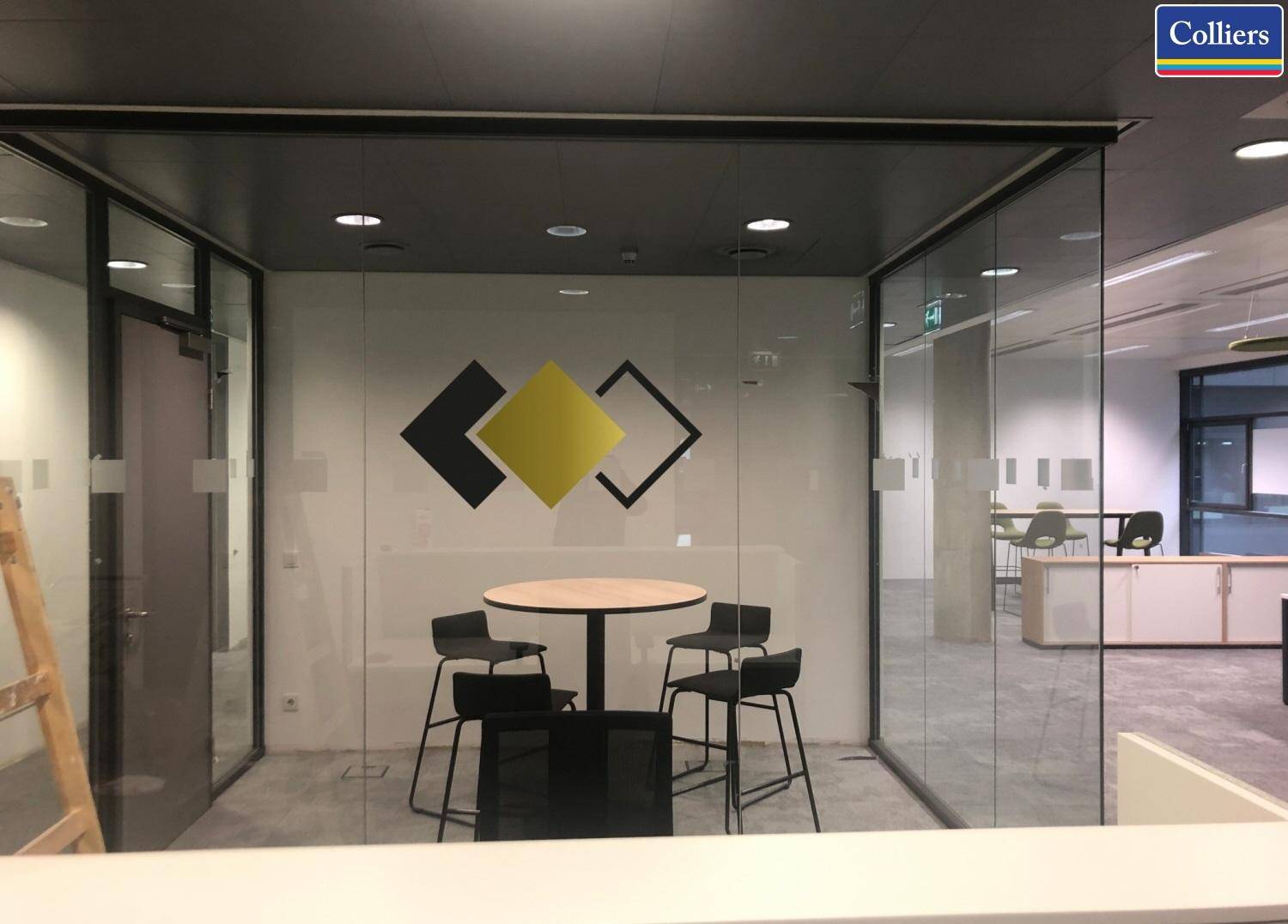 Glasumschlossener Besprechungsraum mit rundem Tisch und schwarzen Stühlen, ideal für kleine Meetings.