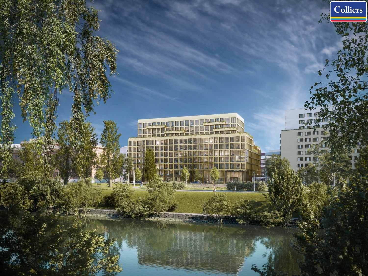 Ansicht des modernen Bürogebäudes vom Flussufer aus, umgeben von Bäumen und Grünflächen.