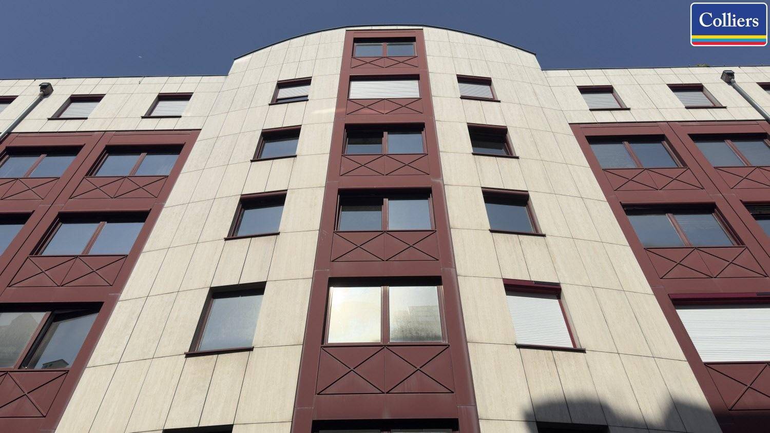 Moderne Gebäudefassade mit abgerundeten Ecken und vielen Fenstern, die eine ansprechende Optik verleiht.