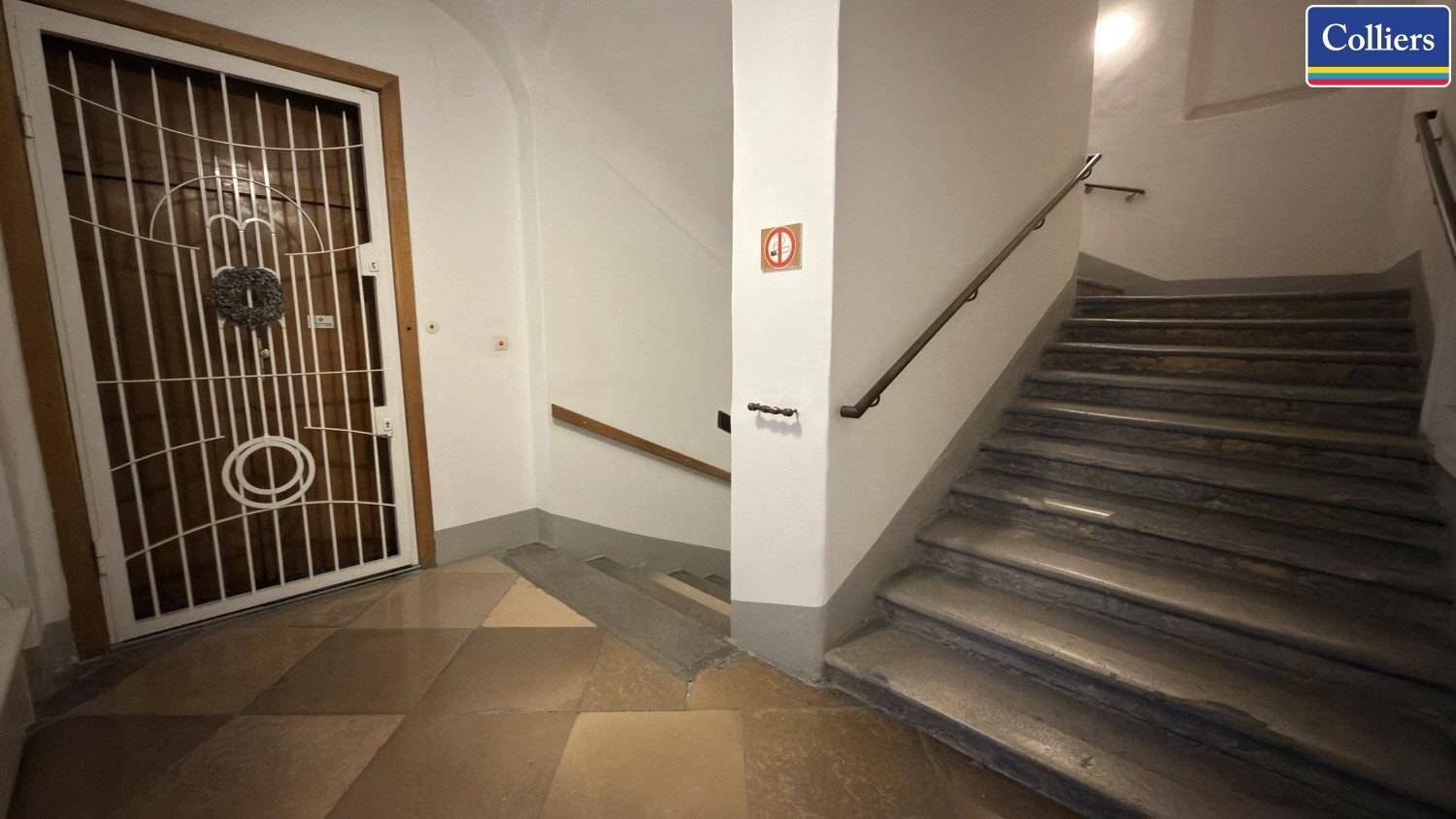 Historisches Treppenhaus mit Steinstufen und Holzgeländer, führt zu den oberen Etagen eines Altbaus.