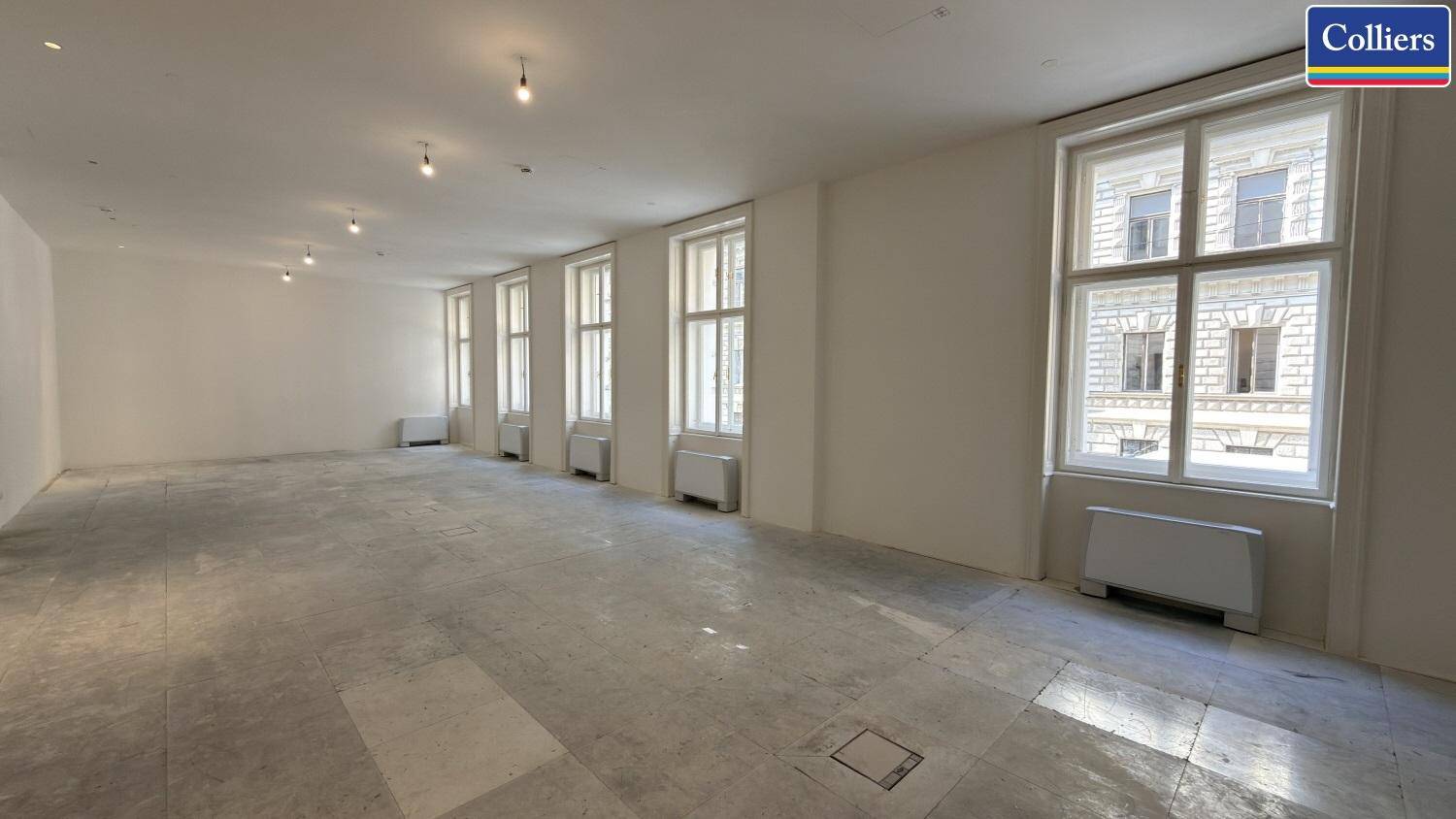 Weitläufiger Bürobereich mit hohen Fenstern und einem hellen Boden, der viel natürliches Licht bietet.