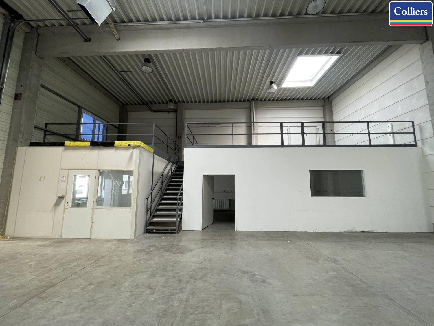 Hohe Lagerhalle mit Betonboden, Zwischengeschoss und Oberlichtern für Tageslicht, industrieller Stil.