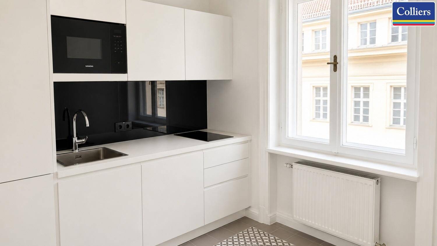 Kompakte, moderne Küchenzeile mit weißen Fronten, schwarzer Arbeitsplatte und Blick aus dem Fenster.