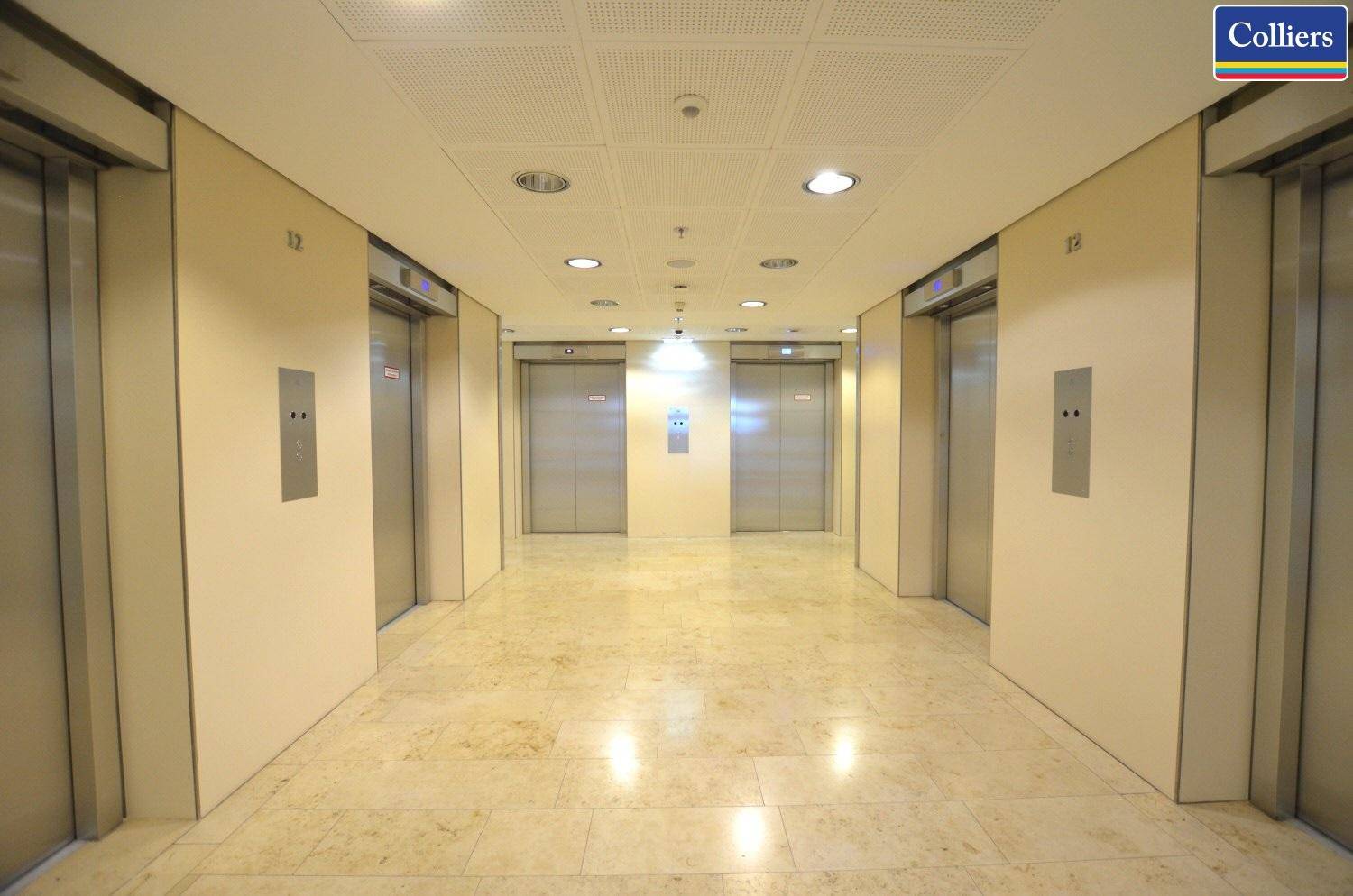 Heller Aufzugsbereich mit mehreren modernen Aufzügen und Marmorboden in einem Bürogebäude, der Funktionalität und Eleganz verbindet.