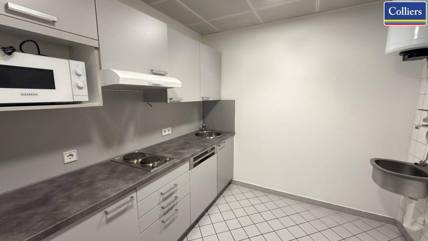 Funktionale Teeküche mit Mikrowelle, Kochplatten und Spülbecken, ideal für die Mitarbeiterversorgung.