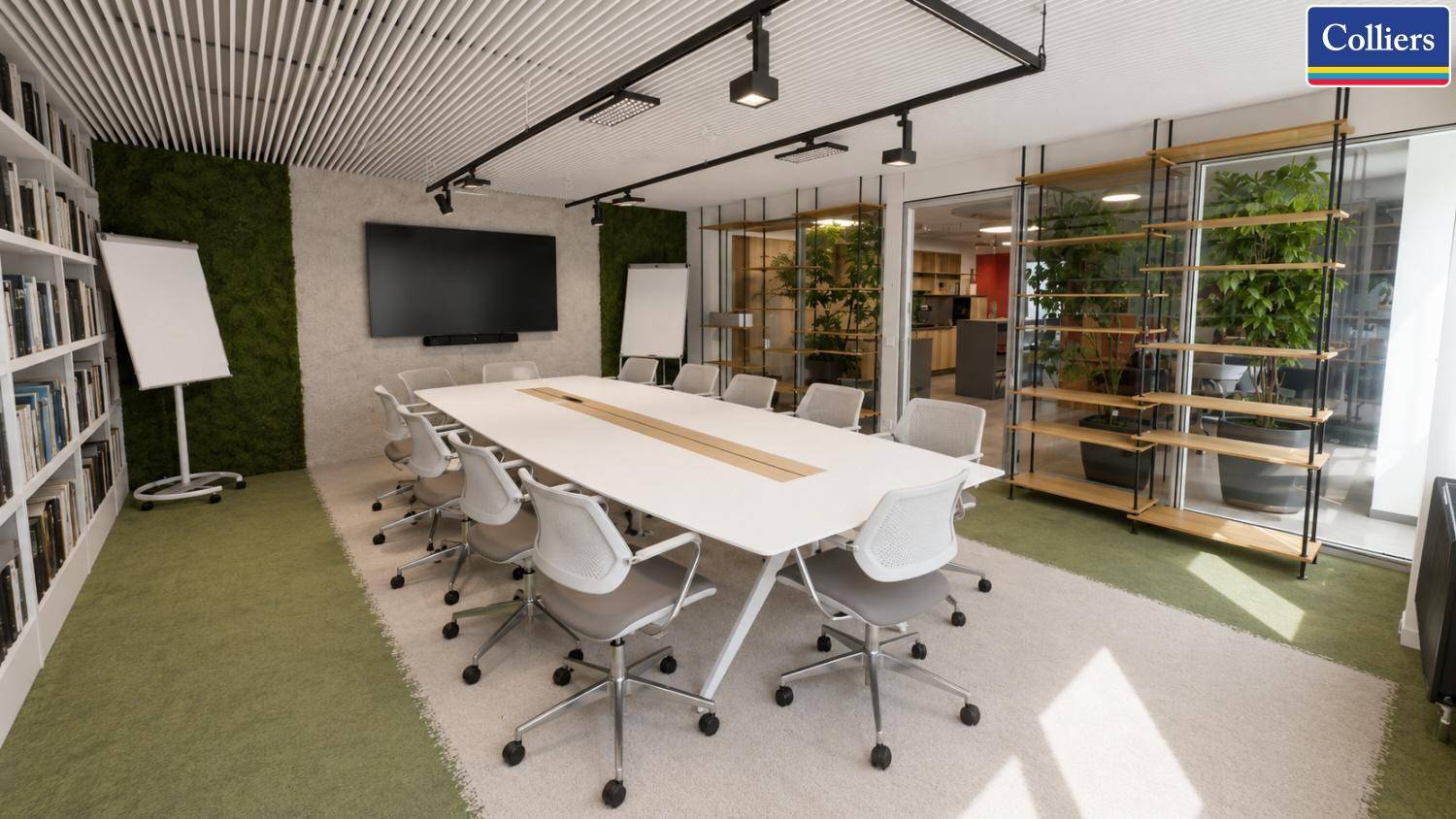 Heller Konferenzraum mit Bücherwand, großem Bildschirm und Blick in einen begrünten Bereich.