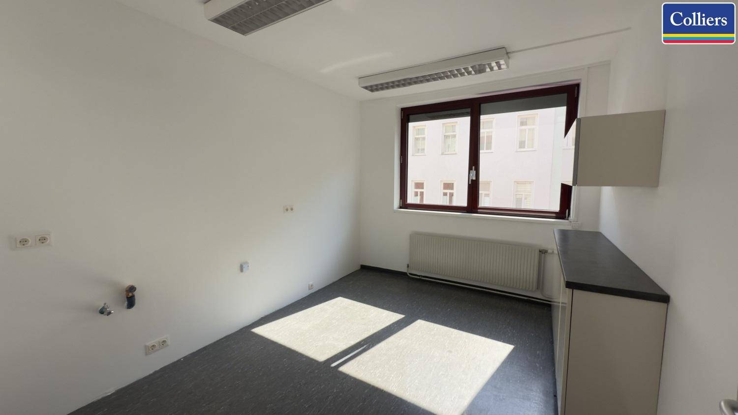 Kleineres Büro mit Teppichboden, einem Fenster und einfacher Einrichtung, ideal für Einzelarbeitsplätze.