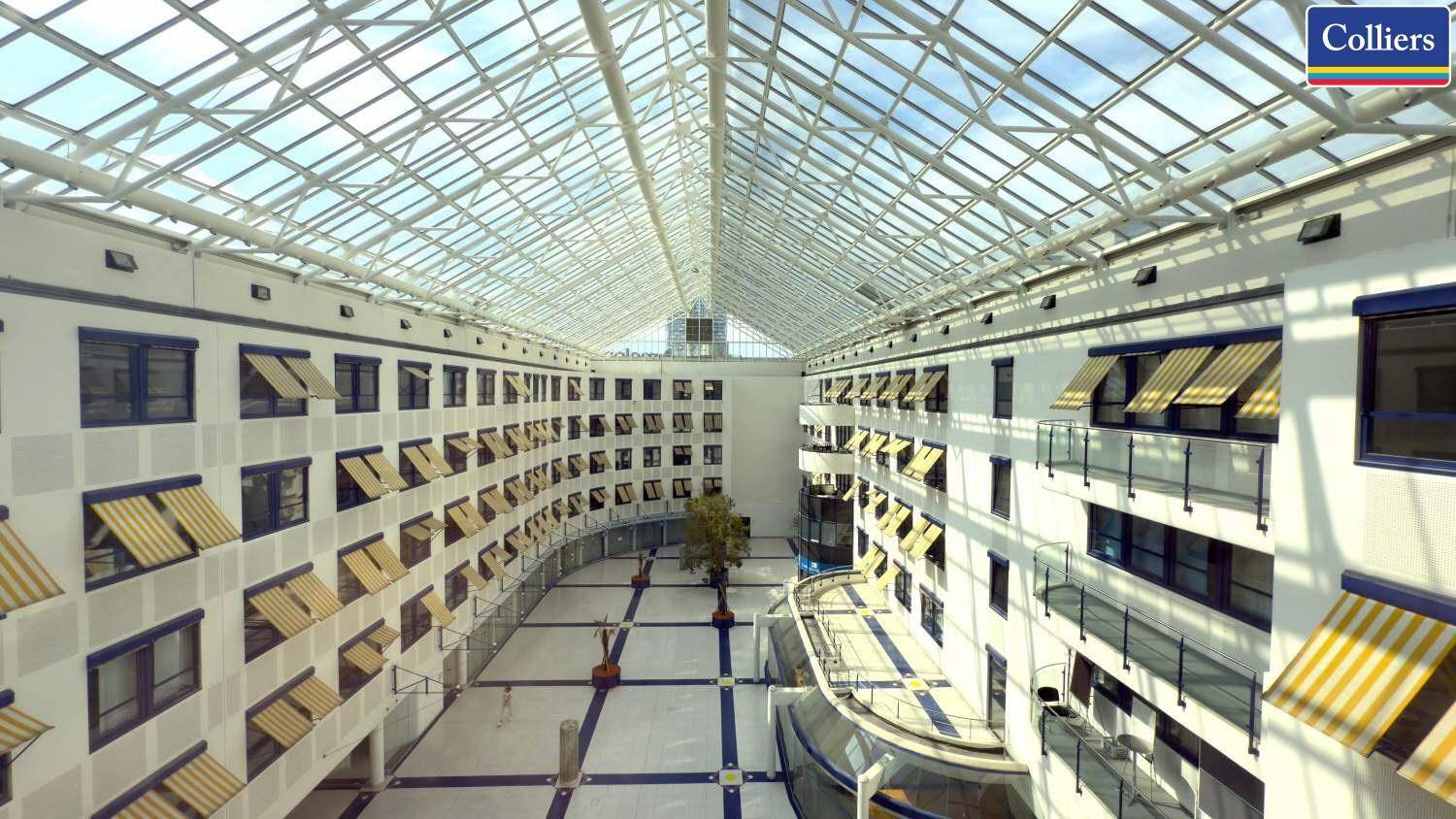Großzügiges Atrium mit Glasdach, das viel Licht spendet und mehrere Etagen verbindet.