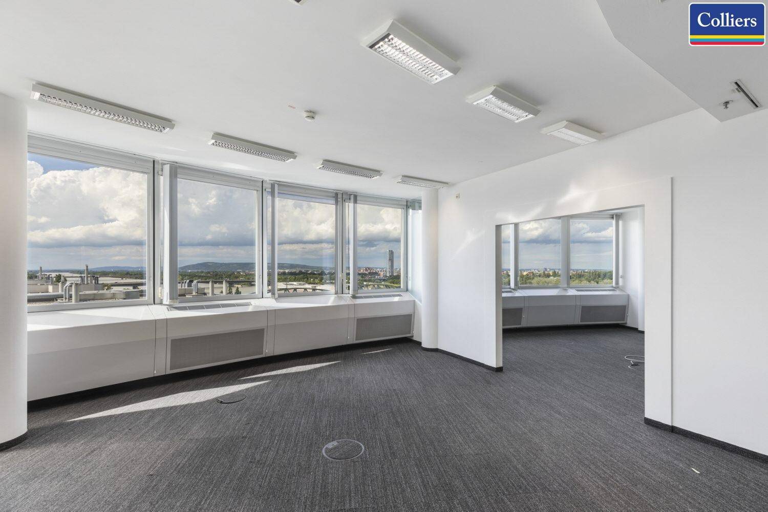 Großer, heller Büroraum mit Teppichboden und vielen Fenstern mit weitem Stadtblick.