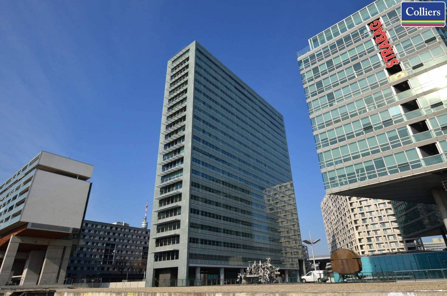 Weitläufige Außenansicht eines modernen Hochhauses mit Glasfassade unter klarem blauem Himmel.