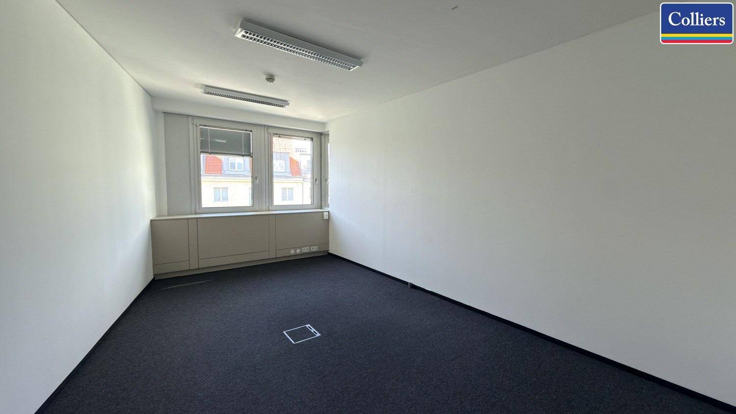 Kleines, helles Büro mit Teppichboden und zwei Fenstern, ideal für konzentriertes Arbeiten.