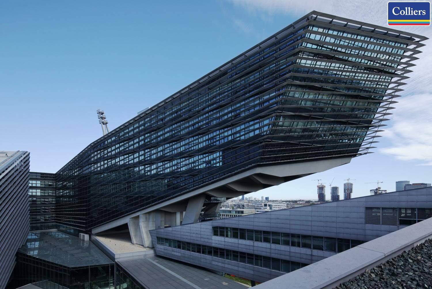 Architektonisch beeindruckendes Gebäude mit auskragenden Elementen und einer weitreichenden Glasfassade unter blauem Himmel.