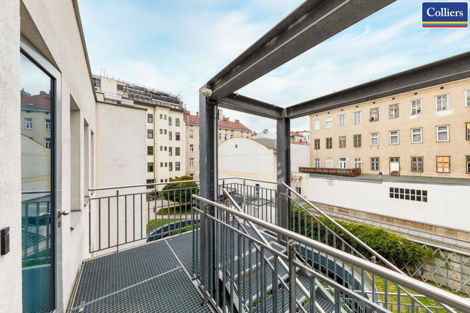 Metallkonstruktion eines Außenbalkons mit Blick auf umliegende Gebäude und den Himmel.