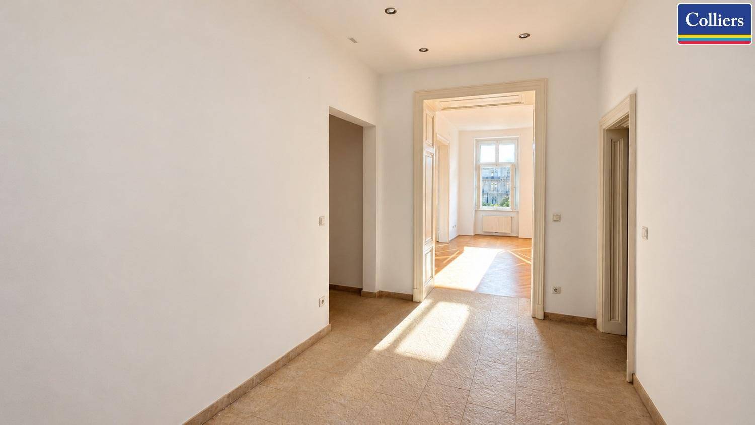 Heller Flur mit Fliesenboden und Durchgang zu weiteren Zimmern, beleuchtet von Sonnenlicht.
