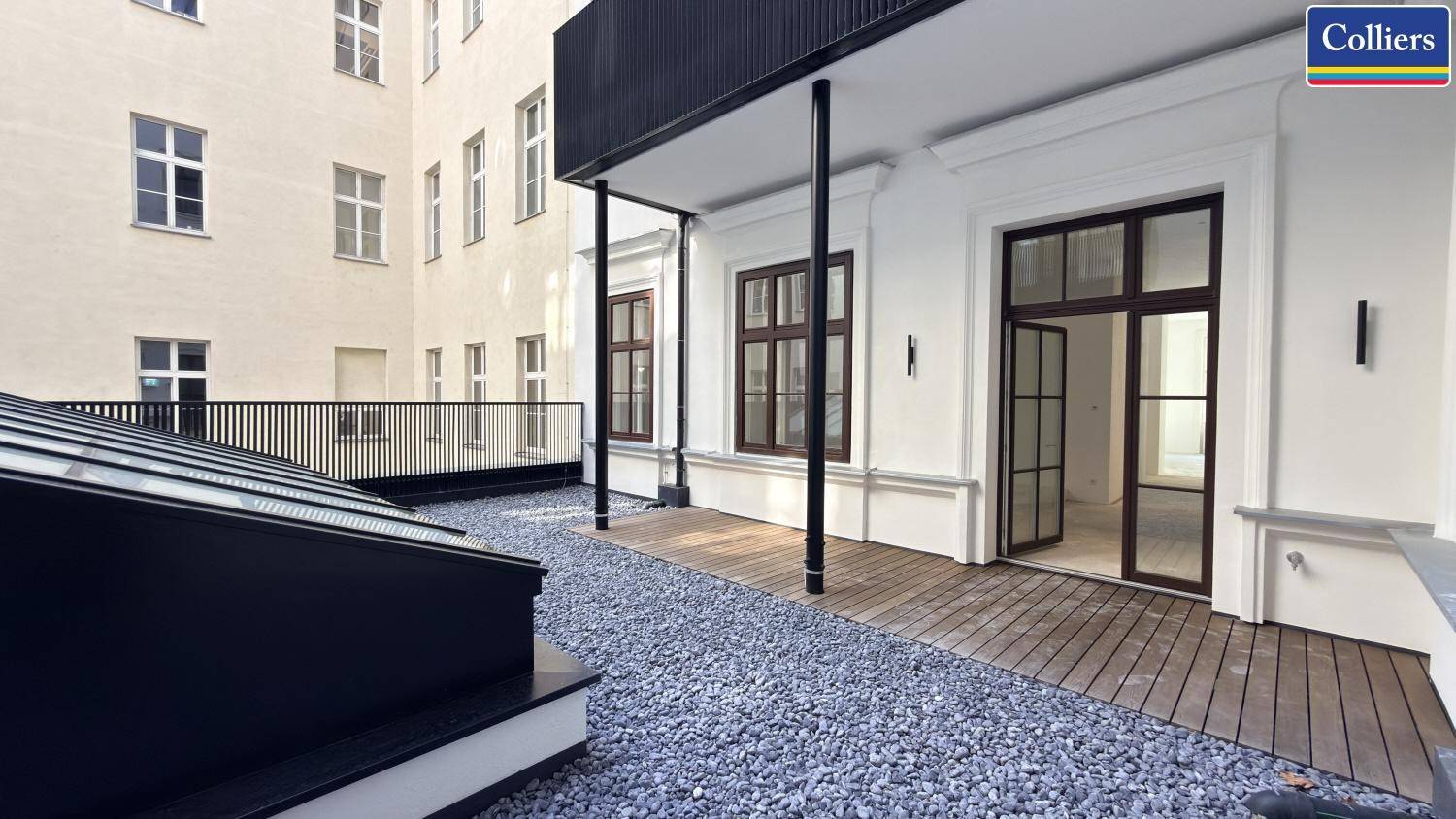 Eine elegante Terrasse mit Holzboden und Zugang zu den Innenräumen des Gebäudes.