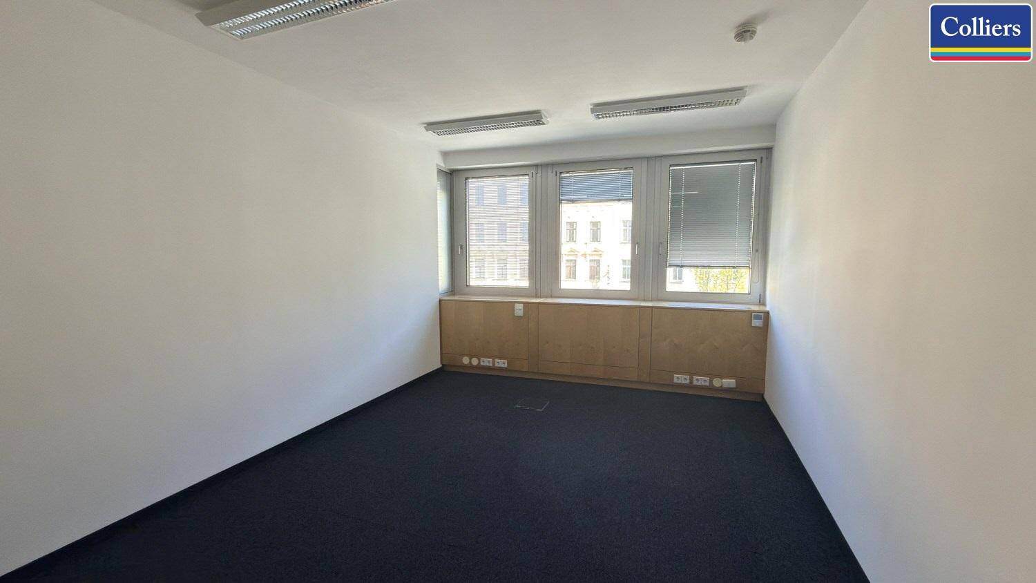 Modernes Büro mit Teppichboden und Fenstern, die einen Blick auf die Stadt bieten und viel Licht spenden.