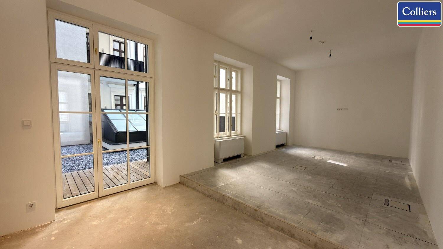 Heller Büroraum mit Zugang zu einer Außenterrasse und Blick auf den Innenhof.