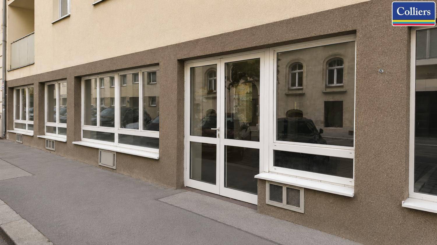 Außenansicht des Gebäudes mit großen Schaufenstern und einer einladenden Eingangstür auf Straßenniveau.
