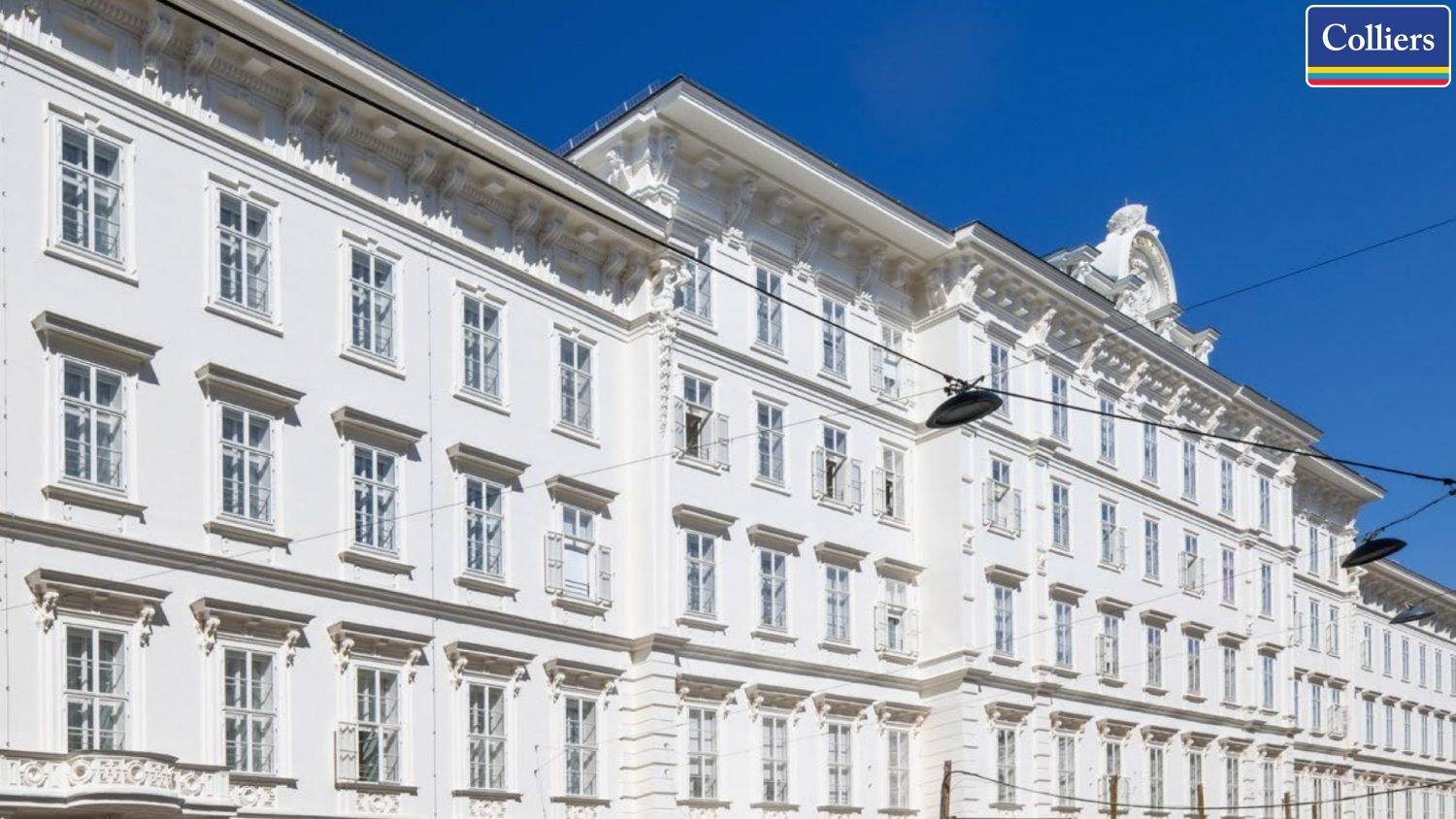 Klassische weiße Fassade eines historischen Gebäudes mit vielen Fenstern und dekorativen Elementen.