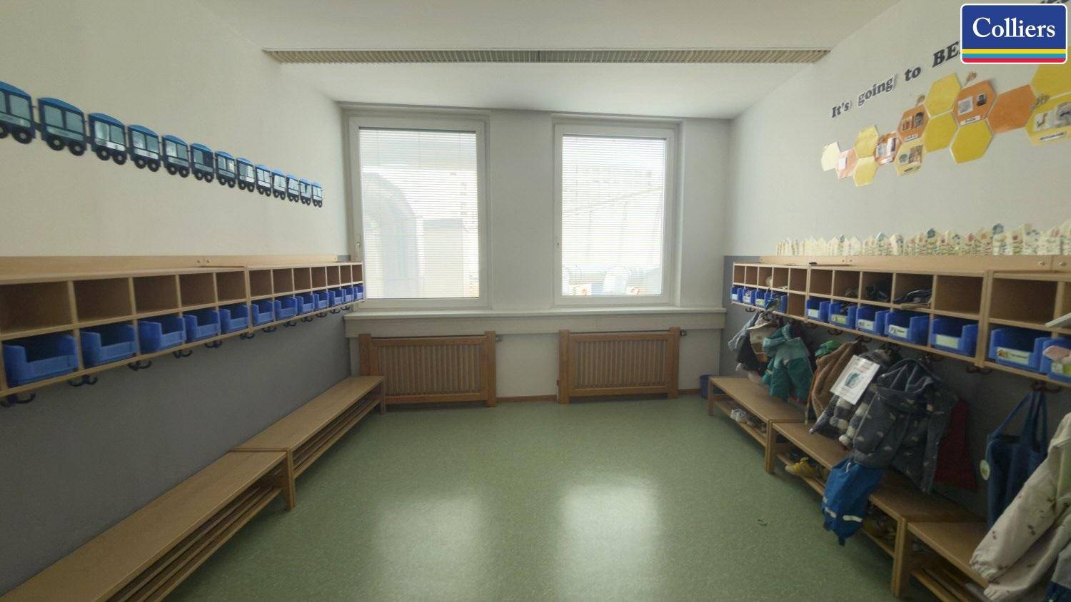 Funktionale Garderobe mit vielen Fächern und Sitzbänken, ideal für Kinder, mit großen Fenstern.