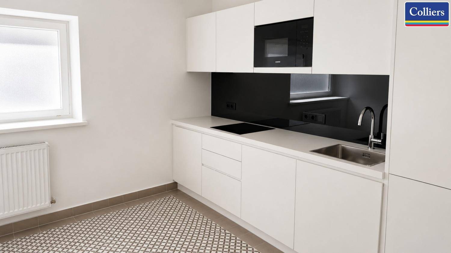 Moderne Küchenzeile mit weißen Schränken, schwarzer Rückwand und integrierten Geräten in hellem Raum.