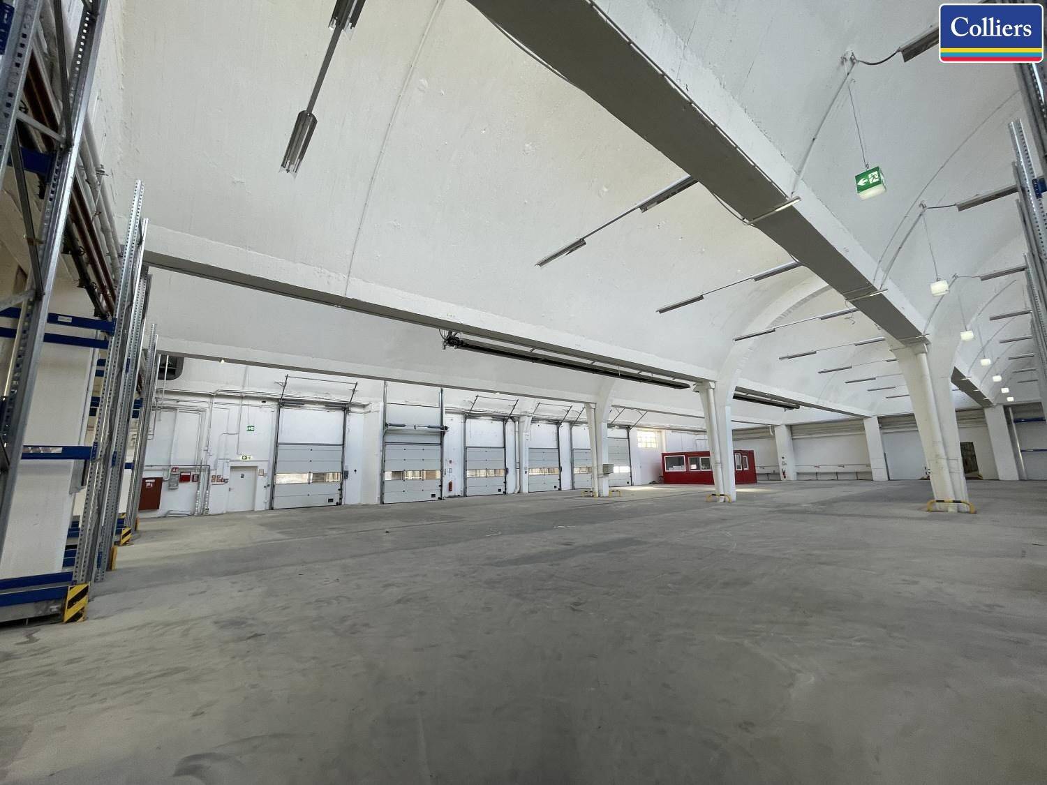 Weitläufige Lagerhalle mit mehreren Rolltoren für Anlieferung und Versand.
