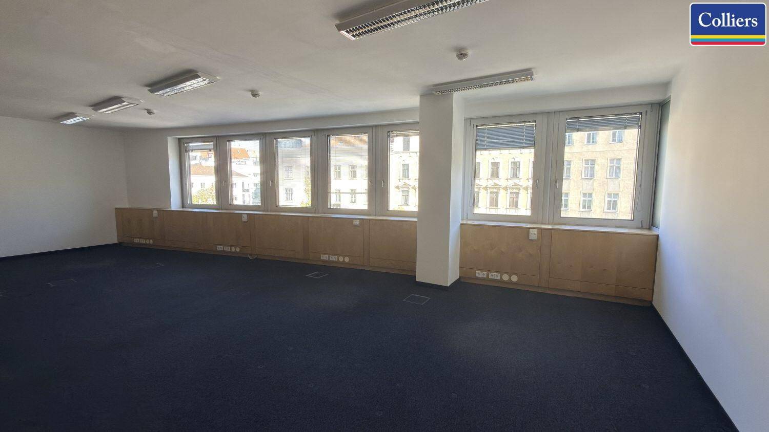 Großer Büroraum mit vielen Fenstern und Teppichboden, ideal für ein offenes Bürokonzept oder mehrere Arbeitsplätze.