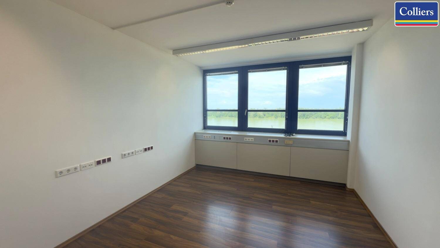 Helles Büro mit Holzboden und einer Fensterreihe, die einen weiten Blick auf die Landschaft ermöglicht.