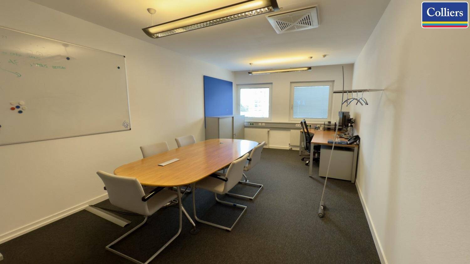Flexibler Bürobereich mit einem Besprechungstisch, Whiteboard und einem einzelnen Arbeitsplatz.