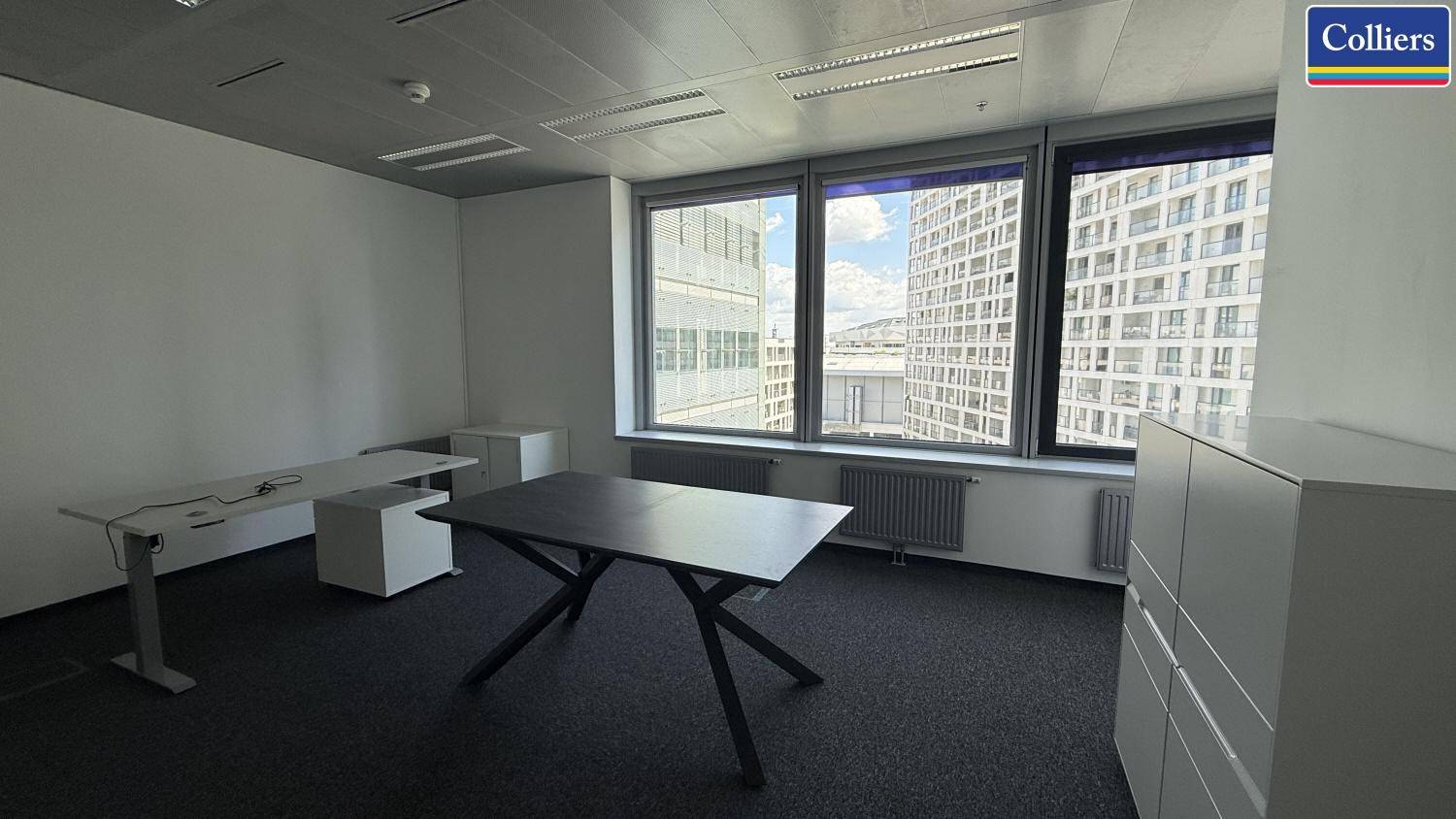 Helles Büro mit großem Tisch und Stauraum, bietet einen weiten Blick auf die Stadtlandschaft.