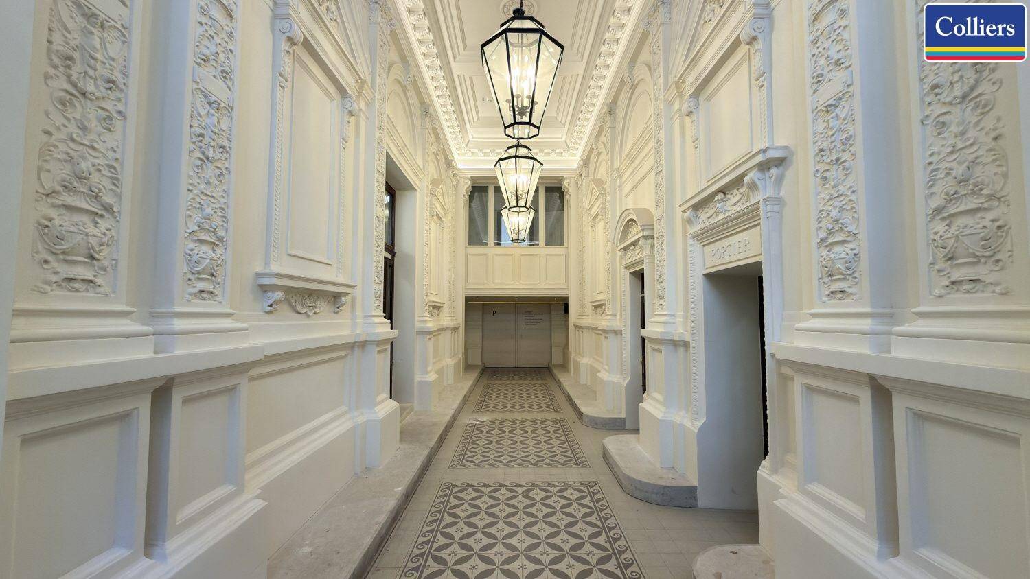 Prunkvoller Eingangsbereich mit Stuckverzierungen, hohen Decken und eleganten Hängelampen, die den historischen Charme betonen.