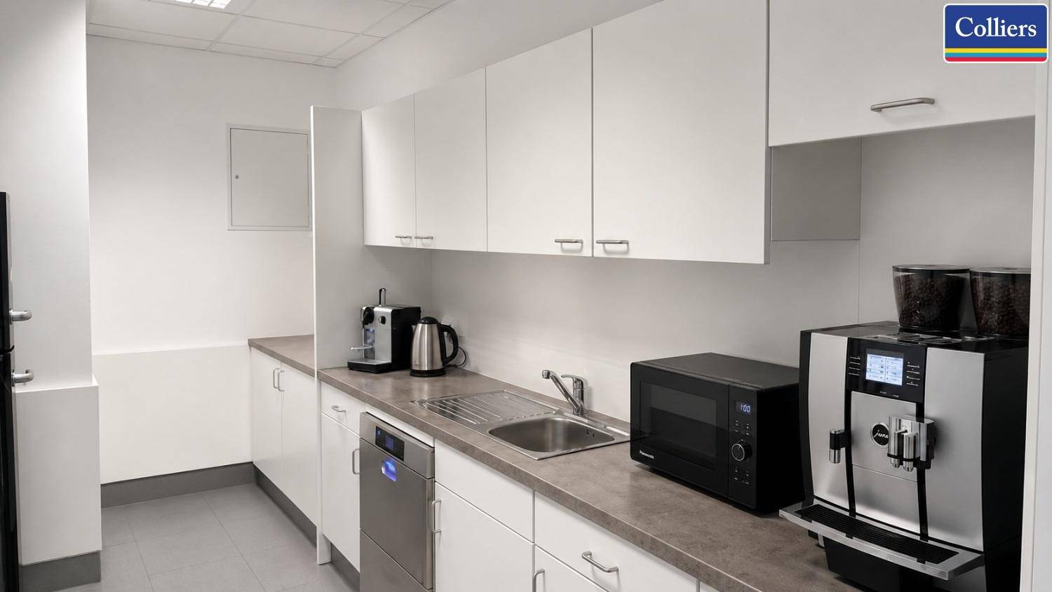 Moderne Teeküche mit weißen Schränken, Spülmaschine und Kaffeemaschine, praktisch für Mitarbeiter.