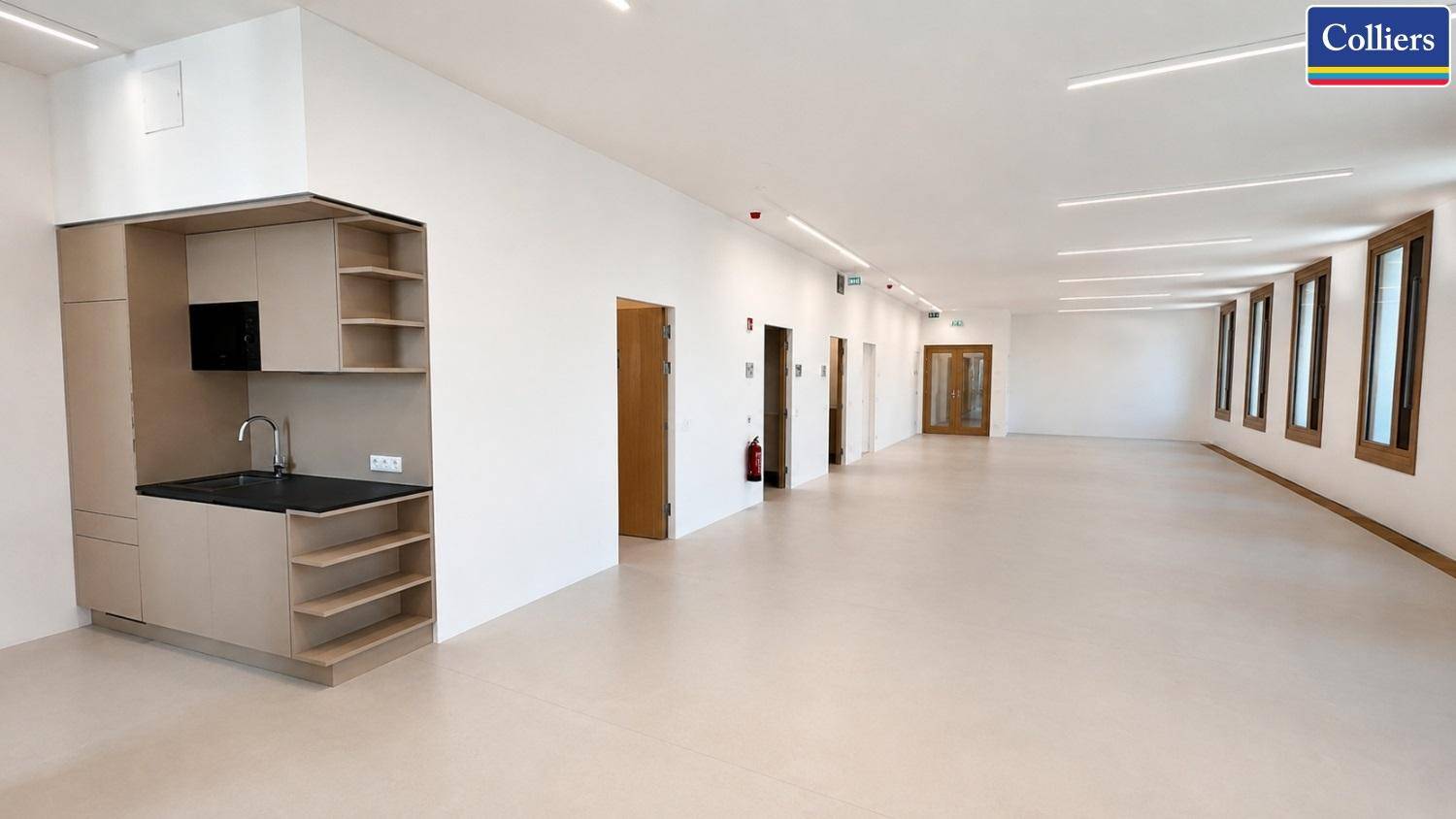 Moderne Küchenzeile in einem offenen Bürobereich mit Zugang zu weiteren Räumen, praktisch und funktional.