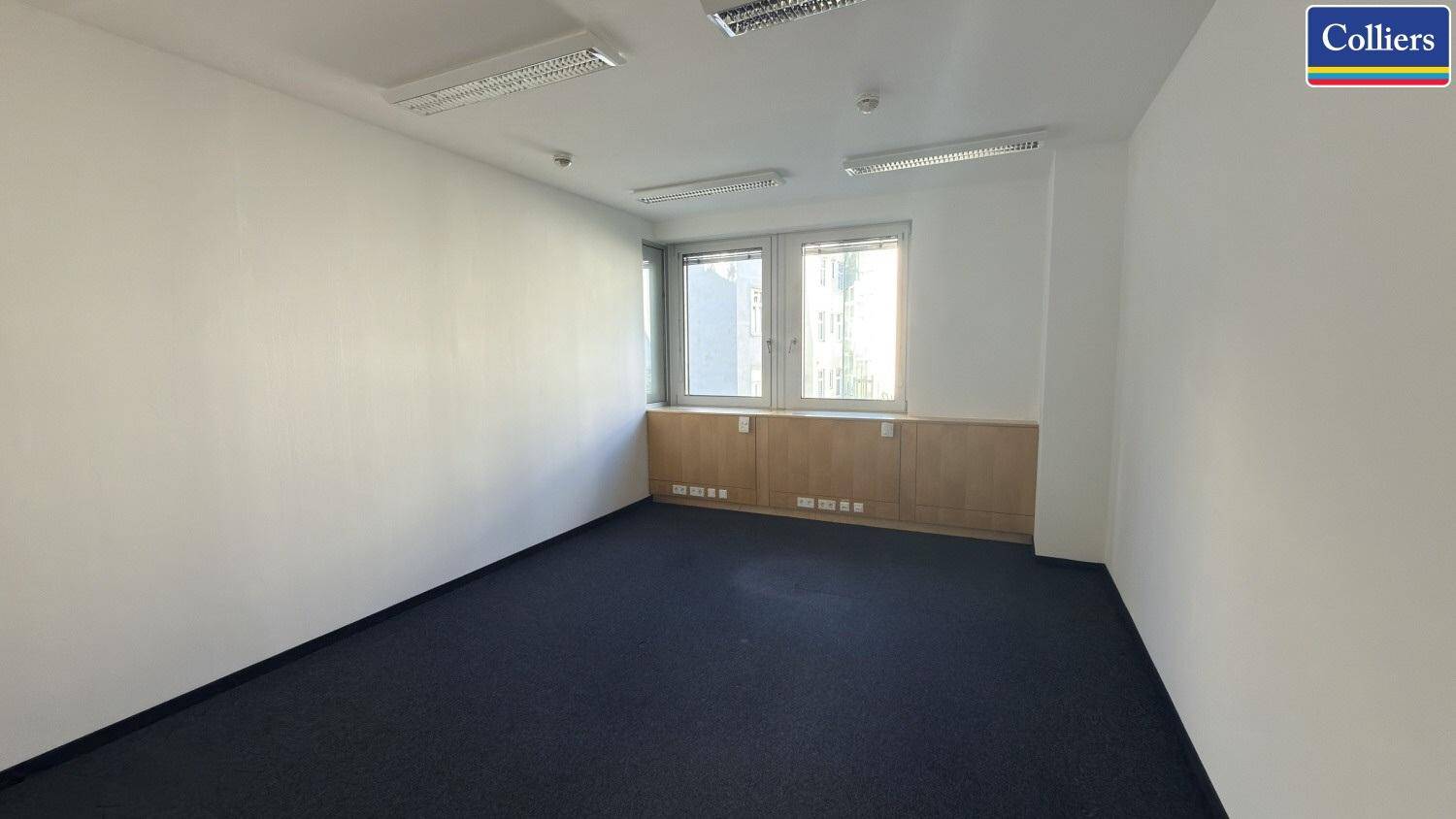 Kleineres Büro mit Teppichboden, zwei Fenstern und weißen Wänden, ideal für Einzelarbeitsplätze oder Besprechungen.