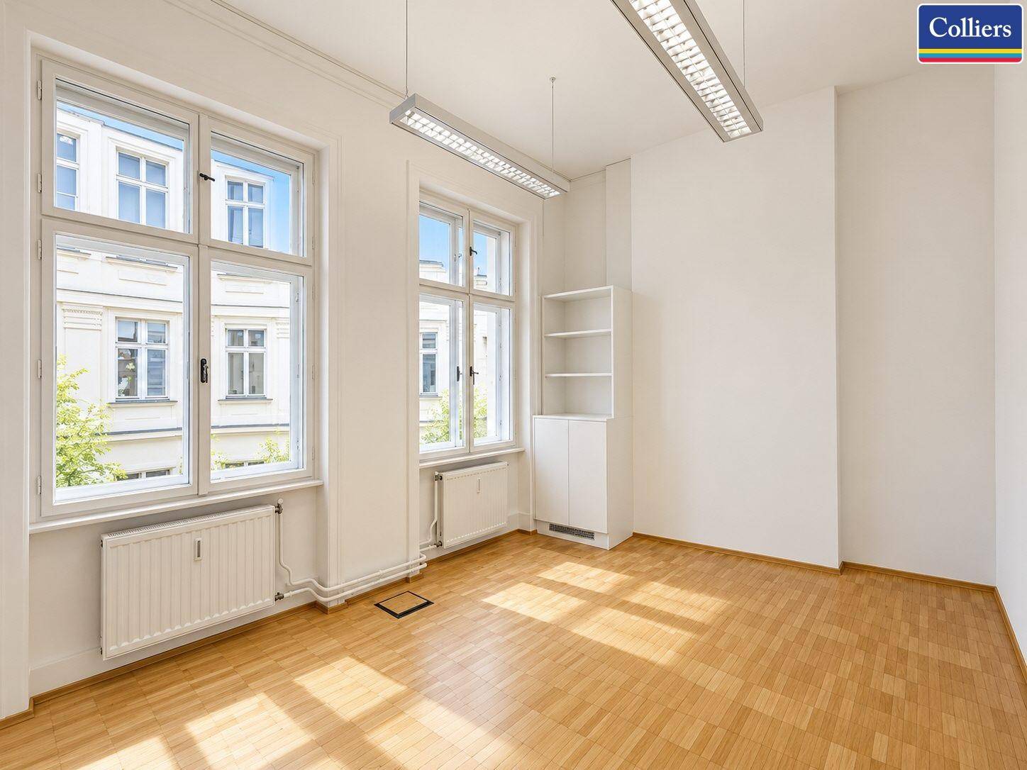 Büro mit Parkettboden, hohen Fenstern und einem Einbauschrank, ideal für Einzelbüros.